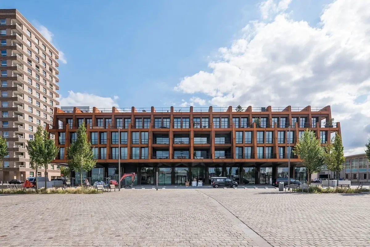 Edifício moderno com fachada de aço cor de ferrugem junto a uma praça pavimentada