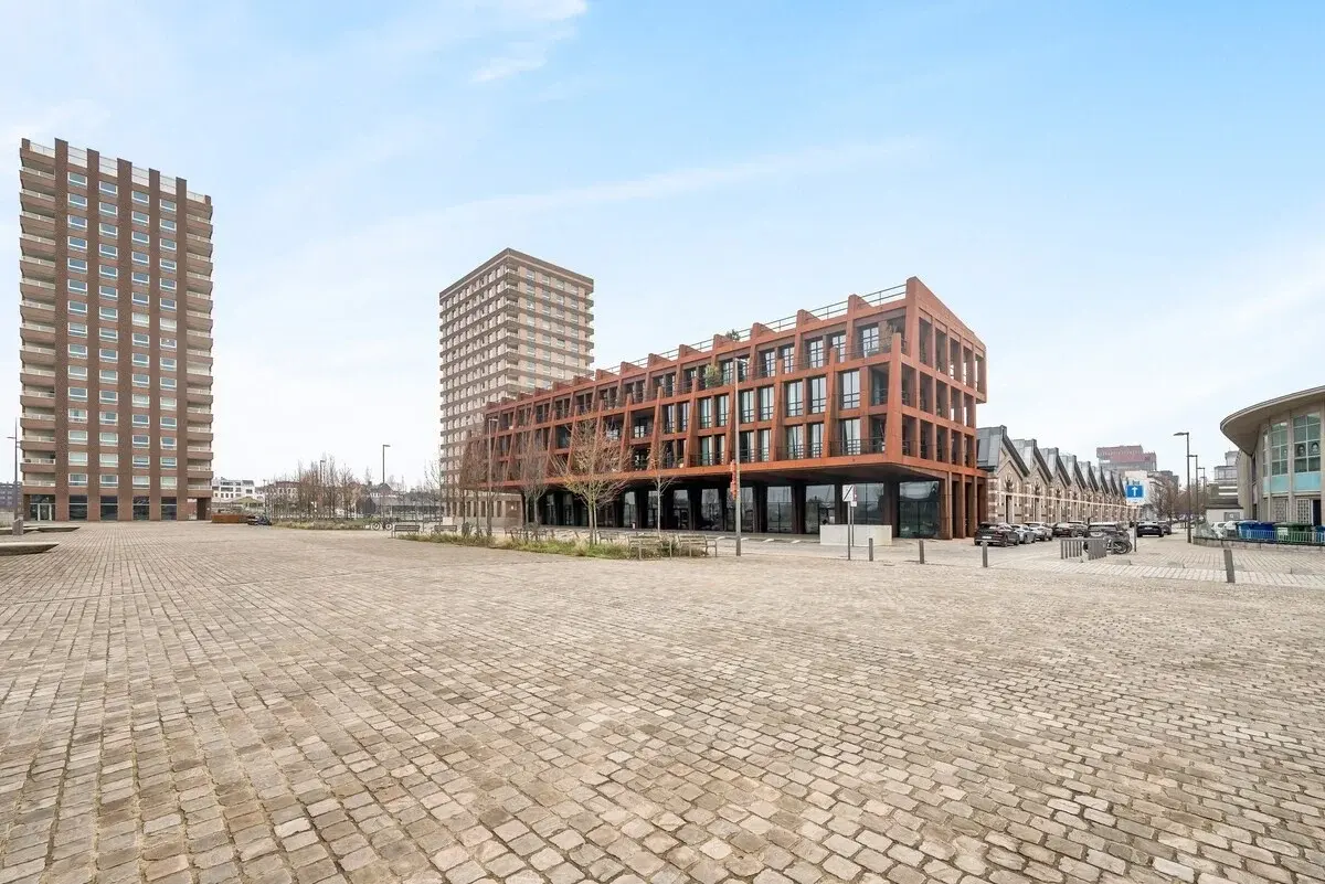 Edifício moderno com fachada de aço cor de ferrugem junto a uma praça pavimentada