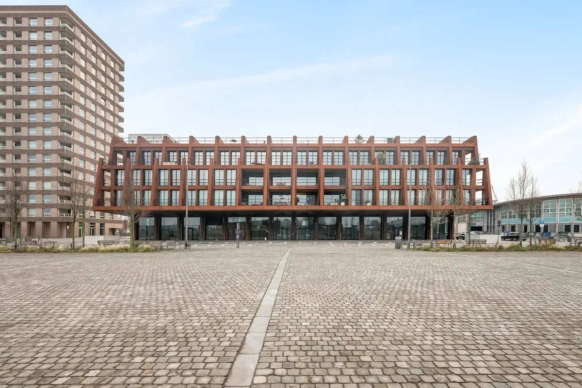 Edifício moderno com fachada de aço cor de ferrugem junto a uma praça pavimentada